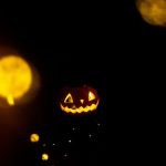 Spooky jack o' lantern illuminated in darkness with bokeh lights, perfect for Halloween imagery.